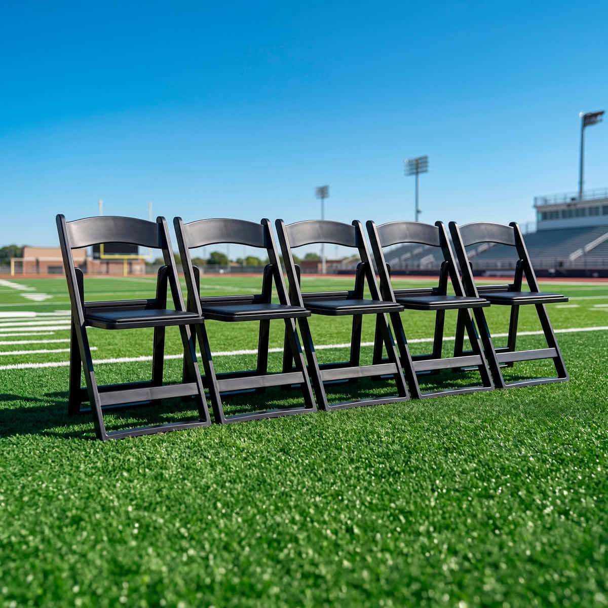 Row of black Grass and Sand Series resin folding chairs on a stadium football field