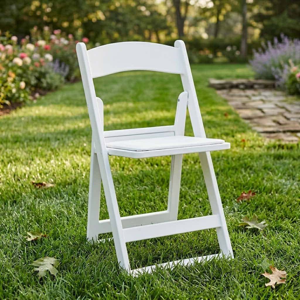 White Grass and Sand Series resin folding chair with white vinyl cushion, set on grass